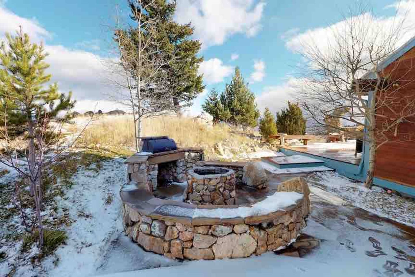 Stone fire pit in winter with pine trees